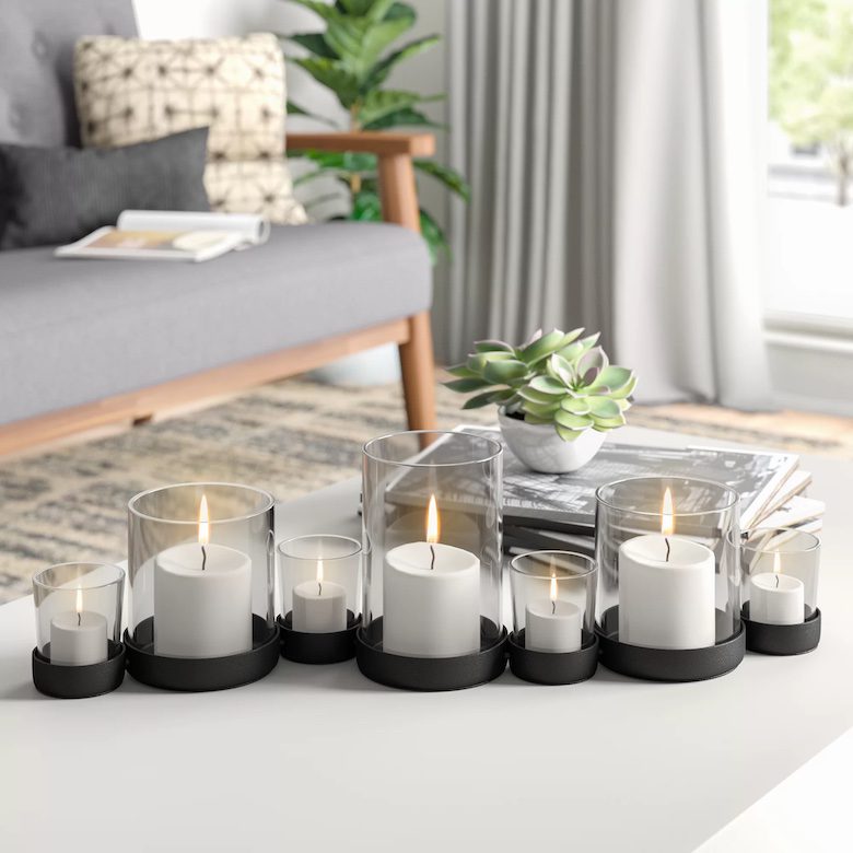 Coffee table with lit candles in glass holders, a small succulent plant, and stacked magazines