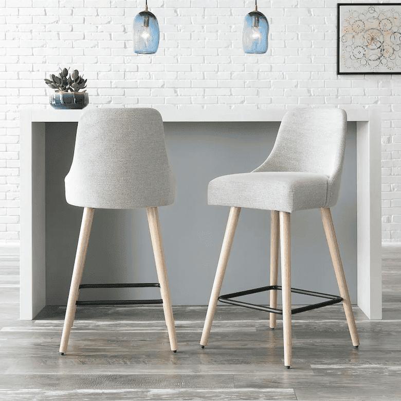 Modern bar stools with light gray upholstery and wooden legs in a bright space