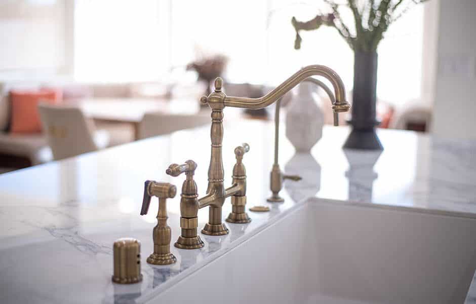 Marble countertop with a brass faucet and sink in a bright kitchen
