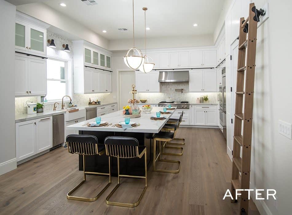 Spacious kitchen with white cabinets, large island, gold-accented chairs, and pendant lighting