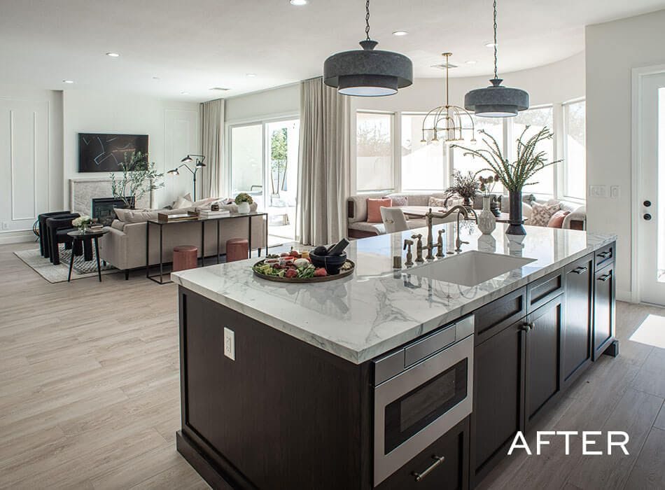 An open-concept kitchen and living room with a large marble island, pendant lighting, and a cozy seating area