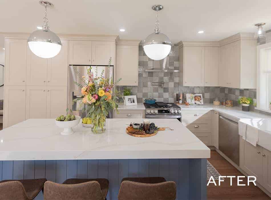 Renovated kitchen with large white island, blue base cabinets, stainless steel appliances, and modern lighting