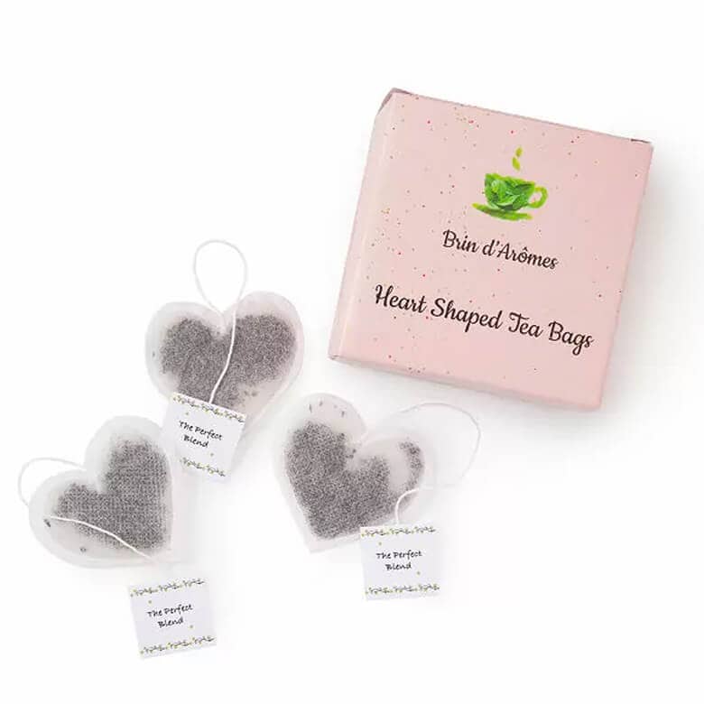 Pink box of Brin d’Arômes heart-shaped tea bags with three heart-shaped tea bags displayed alongside it