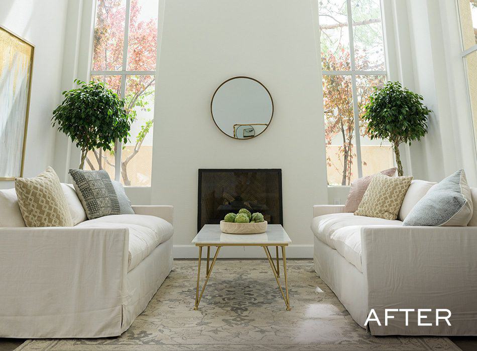 Bright, modern living room with white sofas, large windows, symmetrical greenery, and a minimalist coffee table
