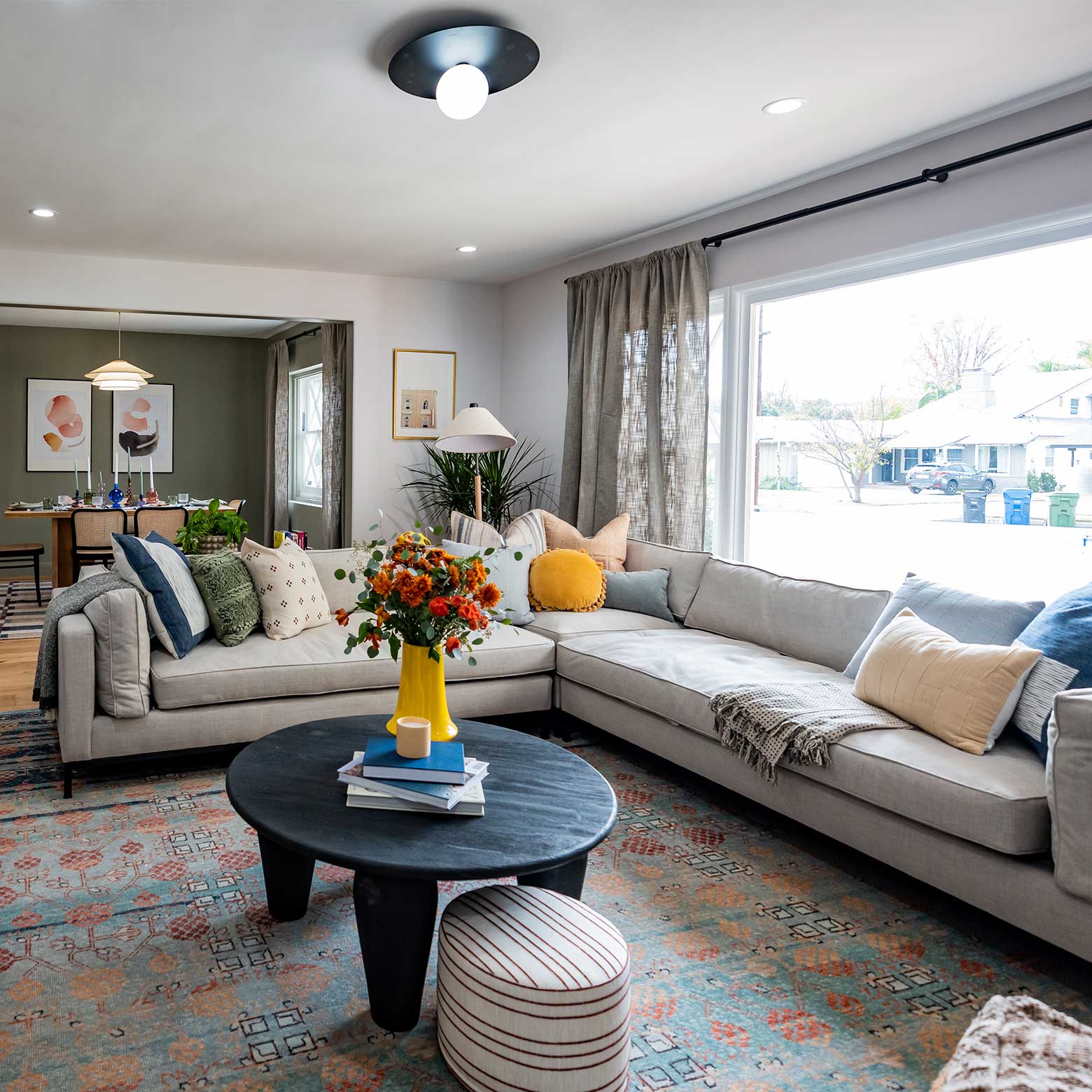 Cozy living room with gray sectional, colorful pillows, and a flower vase on a black coffee table