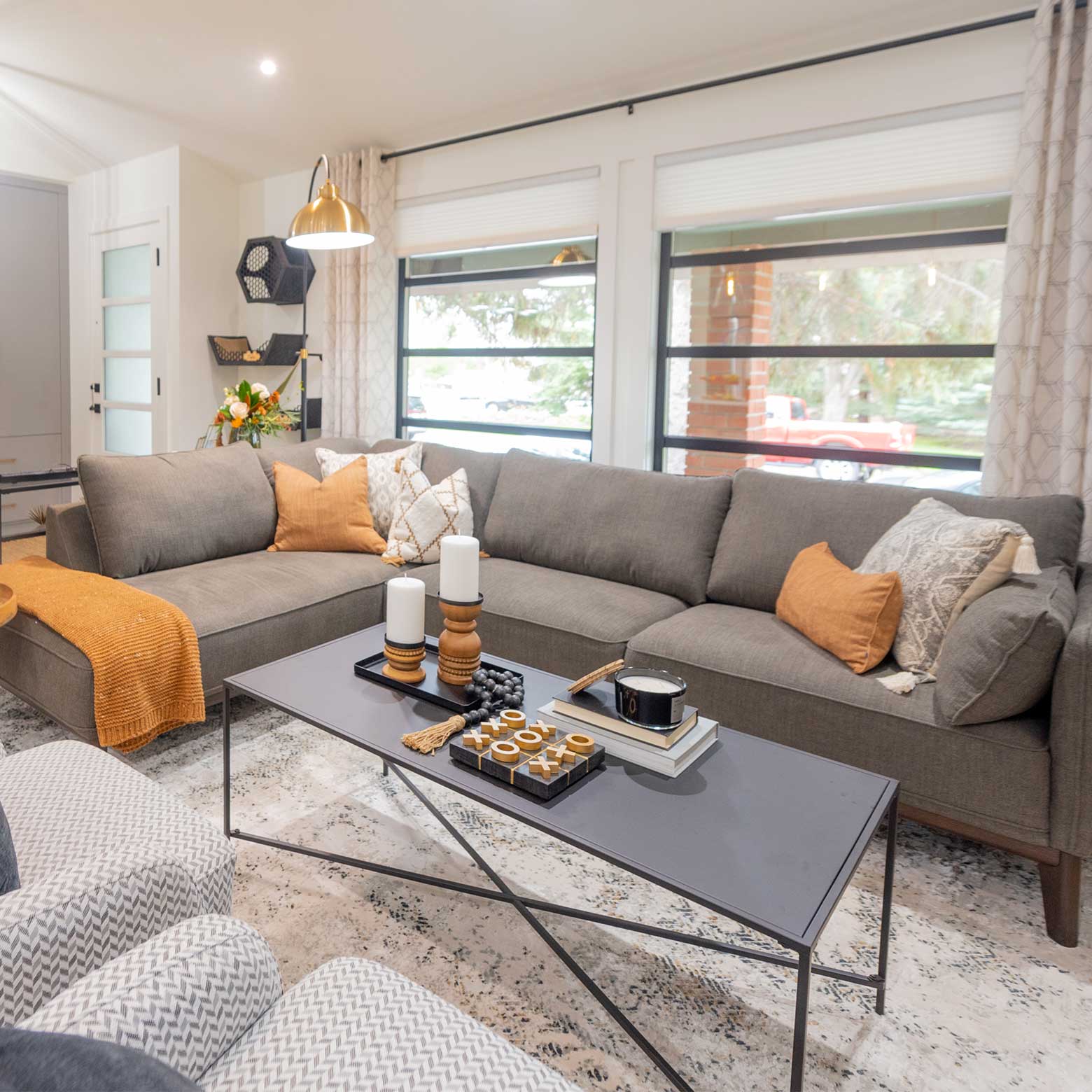Cozy living room with a large gray sectional, mustard accents, and a sleek black coffee table