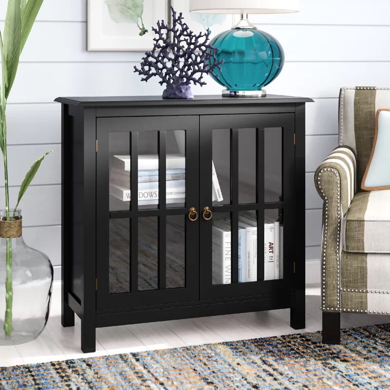 Black glass-front cabinet with gold handles, styled with books and coastal decor