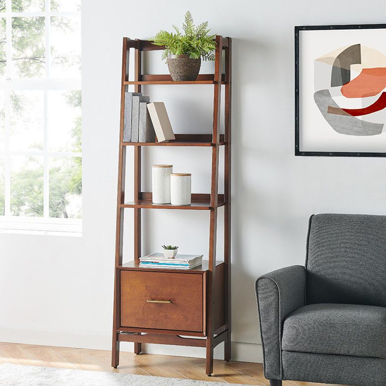 Tall wooden bookshelf with drawer, styled with books, decor jars, and a potted plant