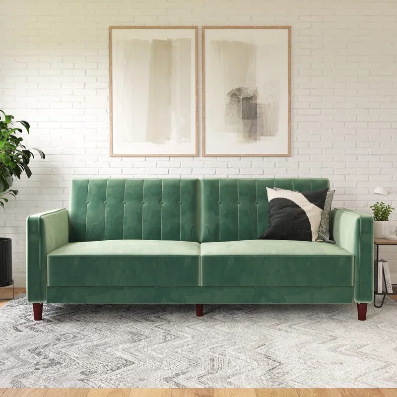 Modern green velvet sofa with tufted backrest, set against a white brick wall with minimalist artwork