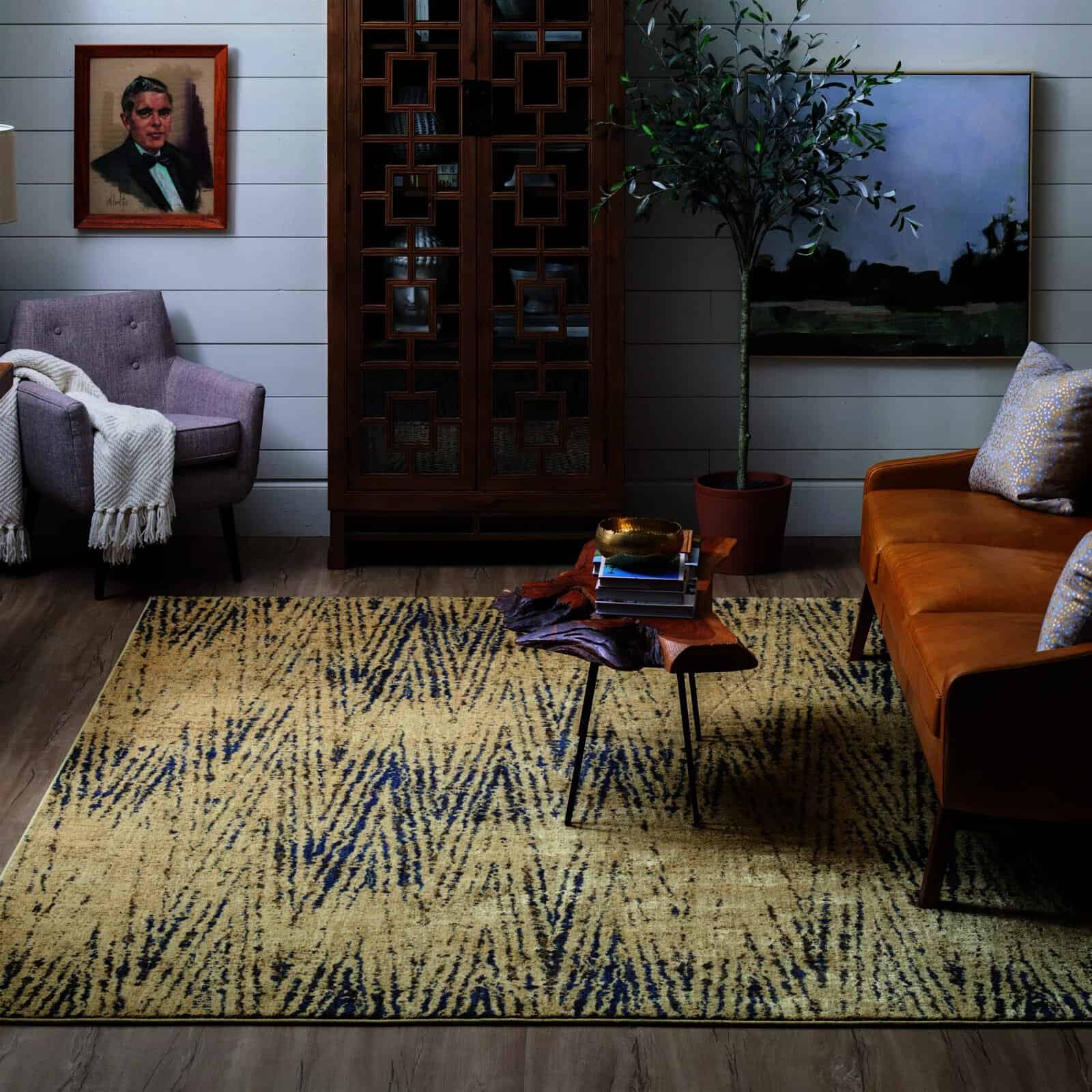 Cozy living room with a patterned rug, brown leather sofa, purple armchair, wooden cabinet, and wall art
