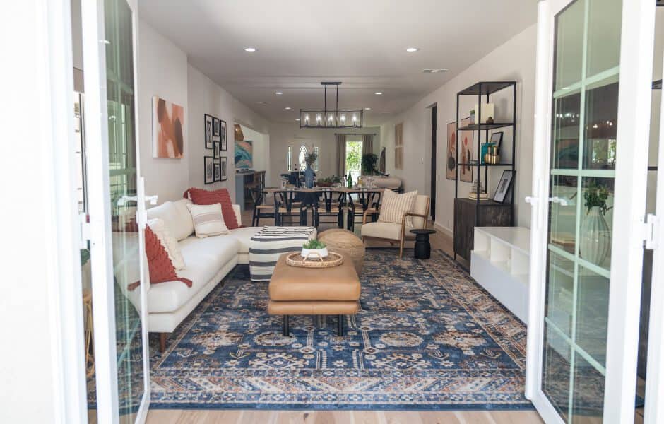 Living and dining area with open French doors blue patterned rug and cozy seating arrangement