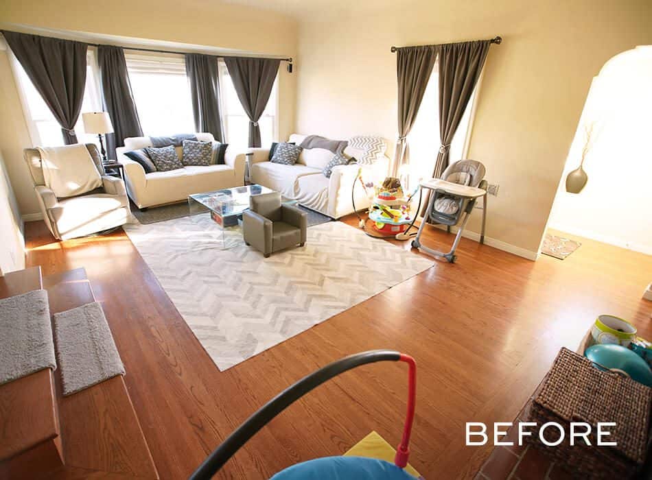 Living room with wooden floors, beige sofas, dark curtains, a glass coffee table, and children's play items