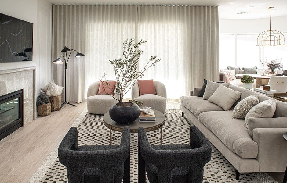 Neutral-toned living room with a beige sofa, black accent chairs, and soft lighting