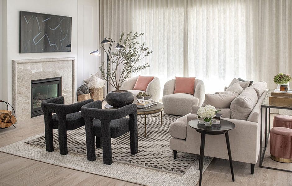 Living room with neutral furniture, black accent chairs, fireplace, and large curtains