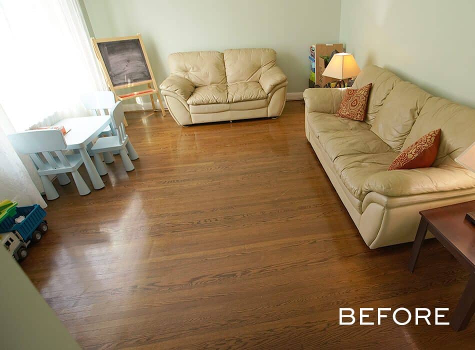 Simple living room with beige sofas, a small play area with a table and chairs, and hardwood flooring