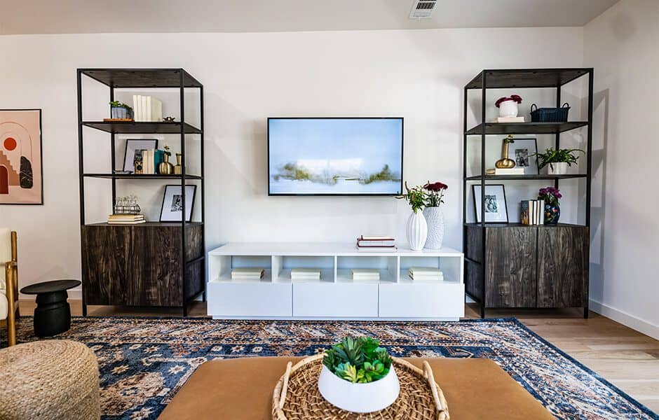 Living room with modern shelving, a mounted TV, and a decorative rug