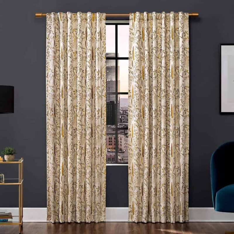 Beige floral-patterned curtains hanging on a gold rod in front of a window