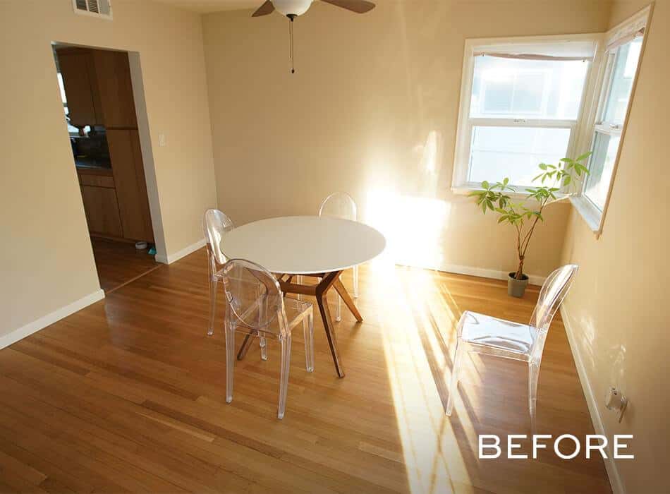 A before image of a simple dining area with a round table, clear chairs, and natural light from windows