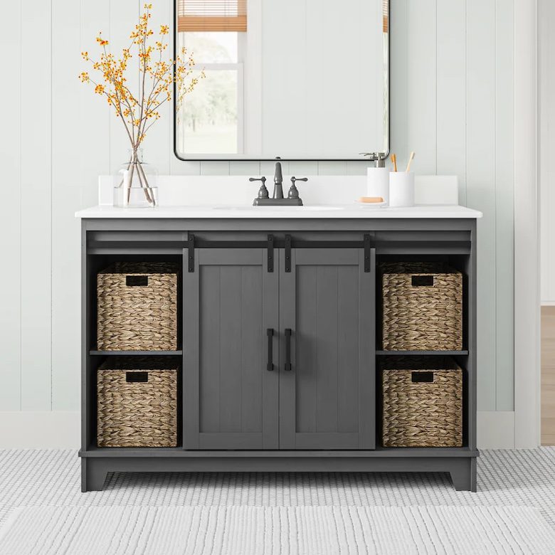 Gray bathroom vanity with sliding barn-style doors, white countertop sink, and woven storage baskets