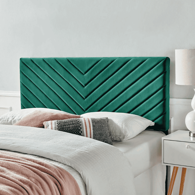 Bed with a green velvet chevron-patterned headboard and cozy layered bedding