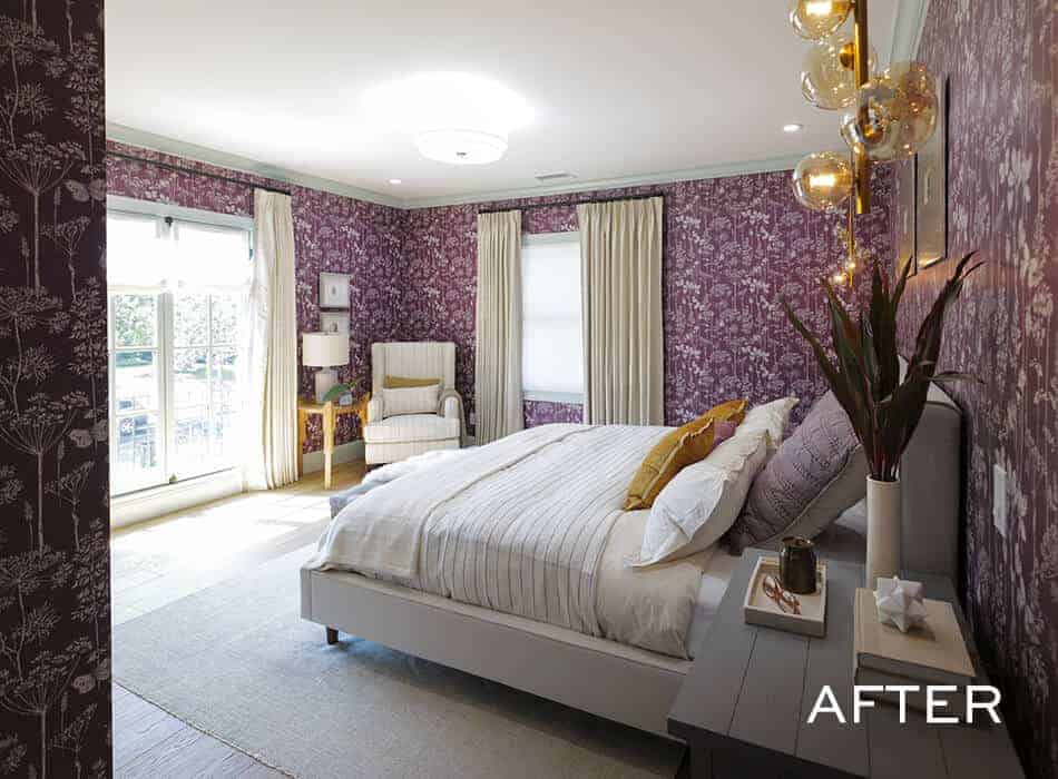 Bedroom with purple wallpaper, a white bed, a gray armchair, and large windows with curtains
