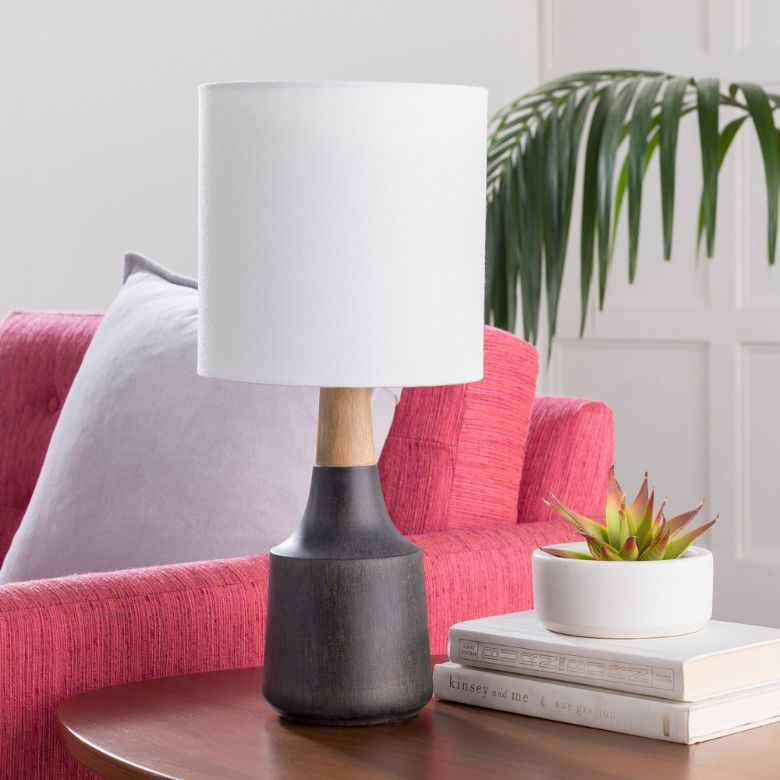 Modern lamp with a black base, succulent, and books on a table beside a pink chair