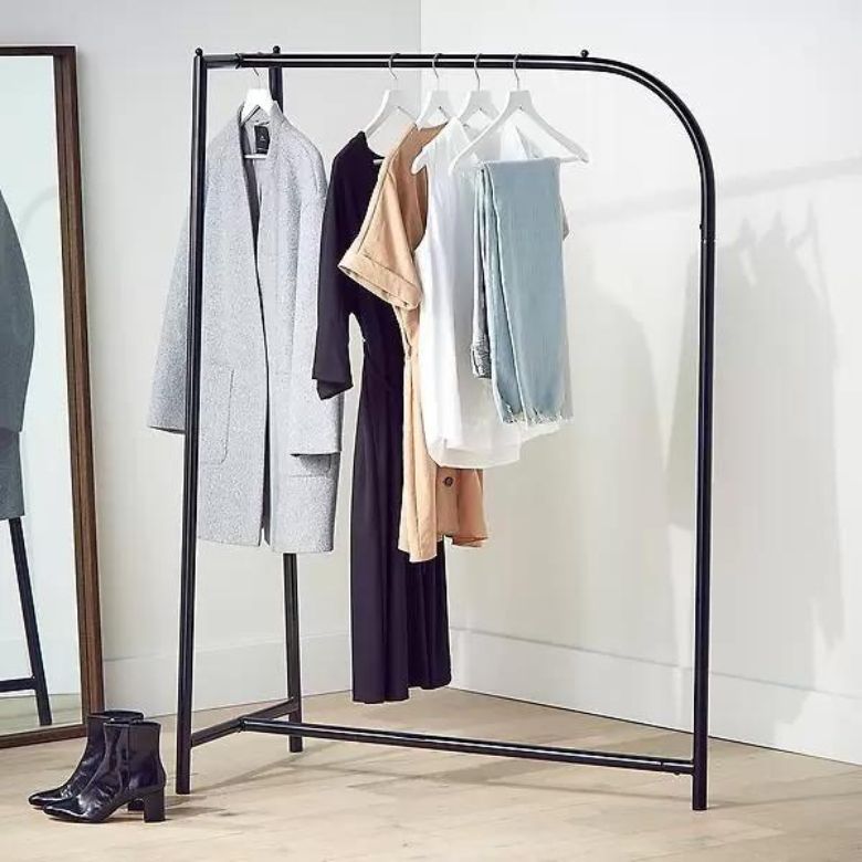 Clothing rack with neutral-toned outfits beside a full-length mirror