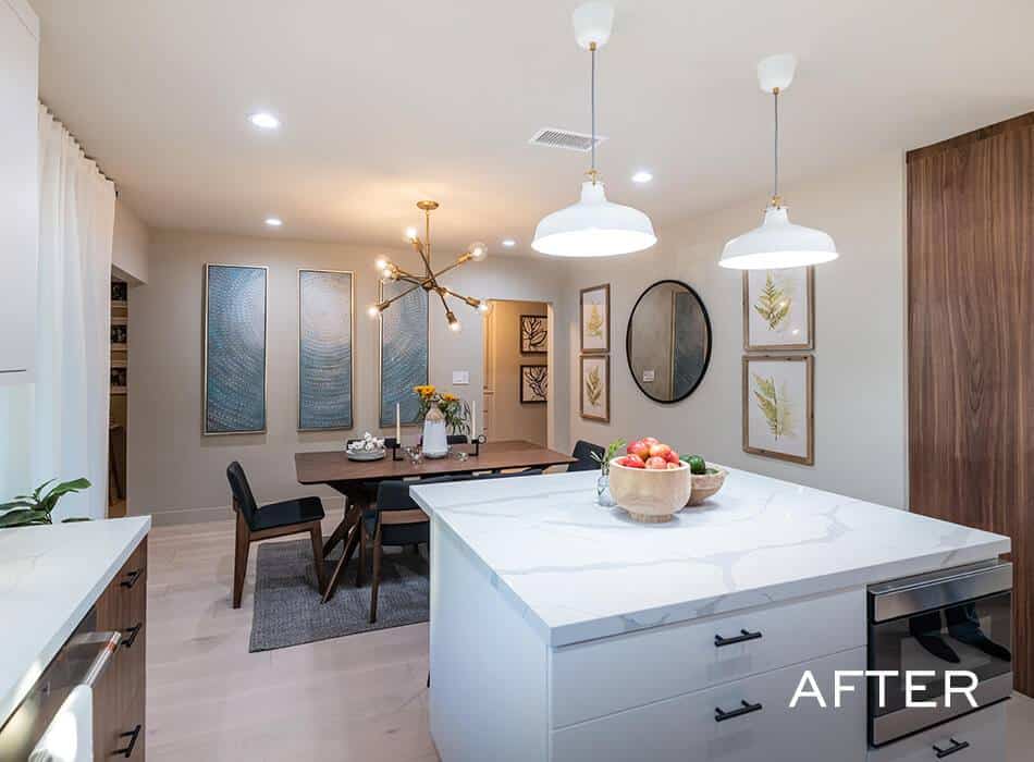Renovated kitchen featuring a white island, statement light fixture, and a wooden dining table