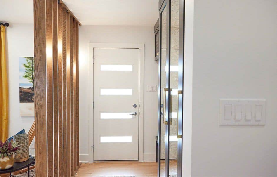 Modern entryway with a white door, wooden slats, and bright decor accents