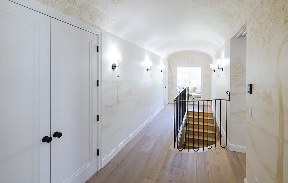 Bright upstairs hallway with arched ceiling, wall sconces, and wooden stairs