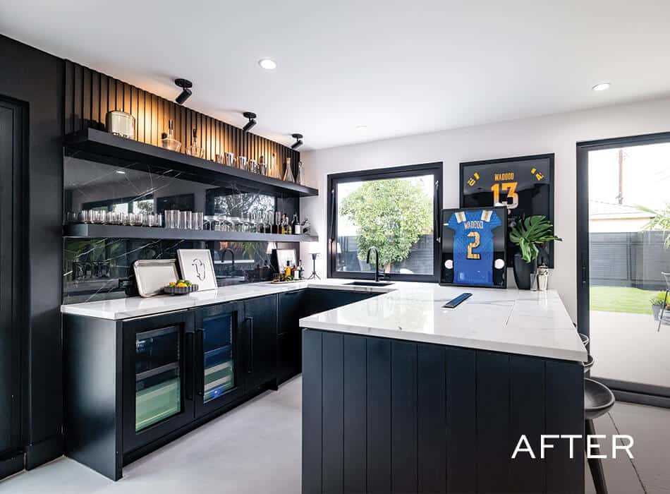 Modern bar area with black cabinetry, white countertops, glassware, and framed sports jerseys on the wall