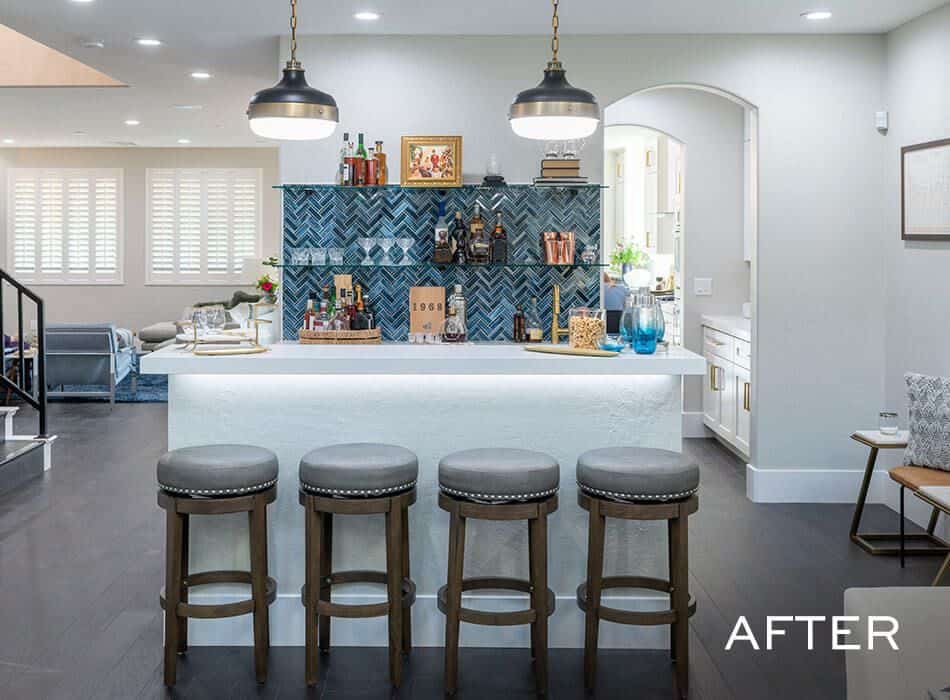 A modern kitchen bar with stools and a vibrant herringbone-patterned backsplash