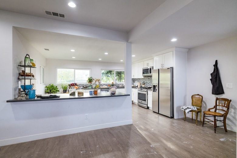 Kitchen with stainless steel appliances, white cabinets, gray countertop bar, and wood flooring