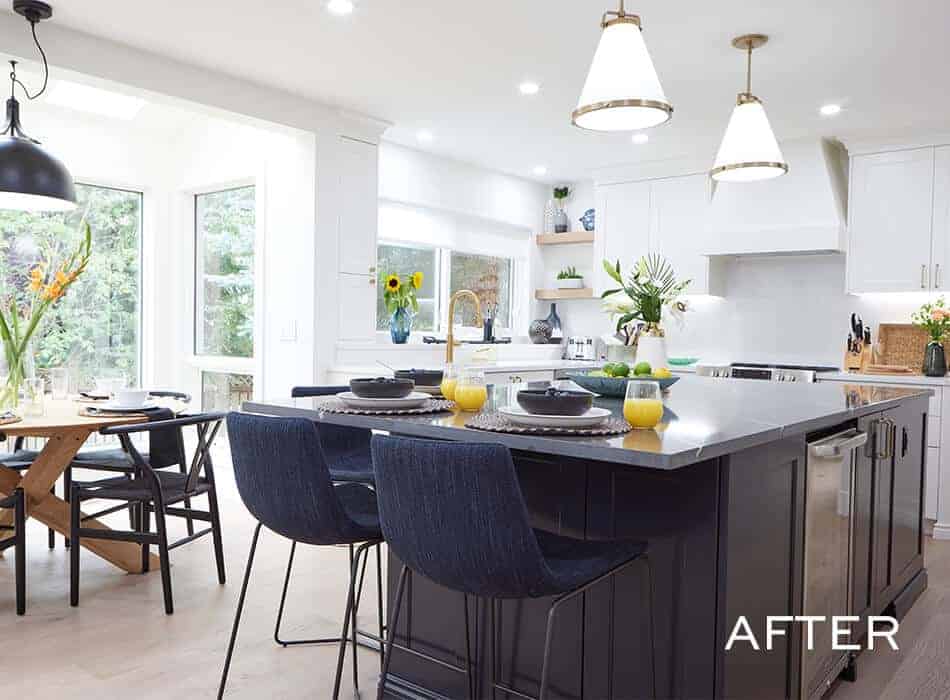 Bright kitchen with a large island, navy barstools, white cabinets, and a dining area with black chairs