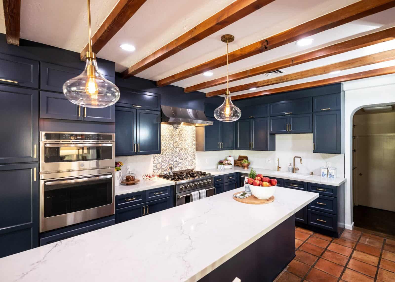 Luxurious kitchen with wood beam ceilings, navy cabinets, and stainless steel appliances