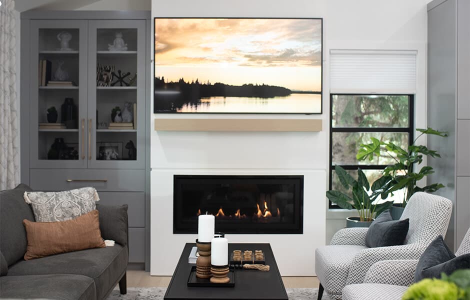 Contemporary living room with fireplace, built-in shelving, and a wall-mounted TV displaying a landscape