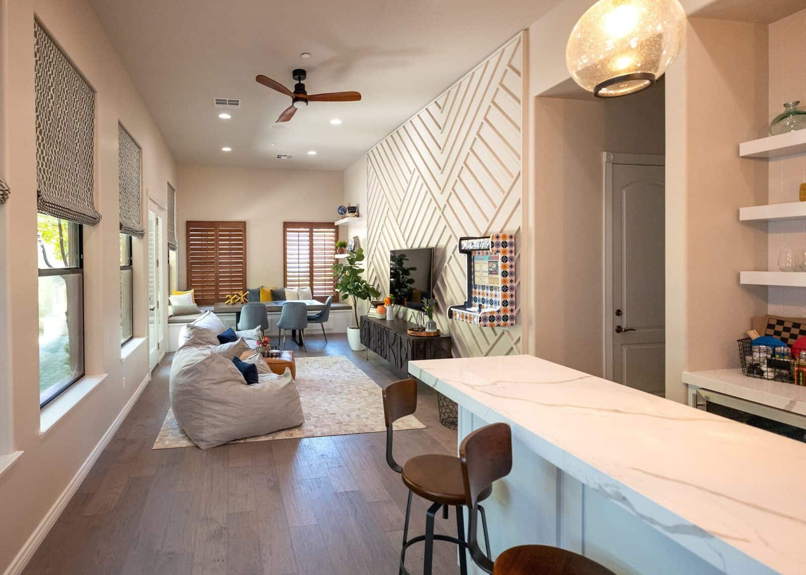 Spacious living room with a white marble countertop, wooden bar stools, and a comfortable seating area with a large TV