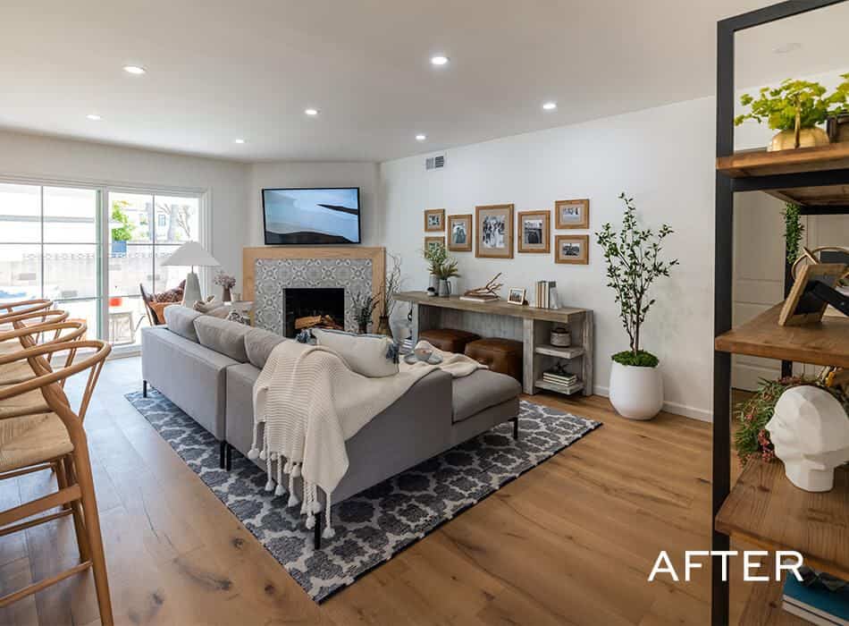 Renovated living room with modern decor, comfortable seating, fireplace, and framed photos