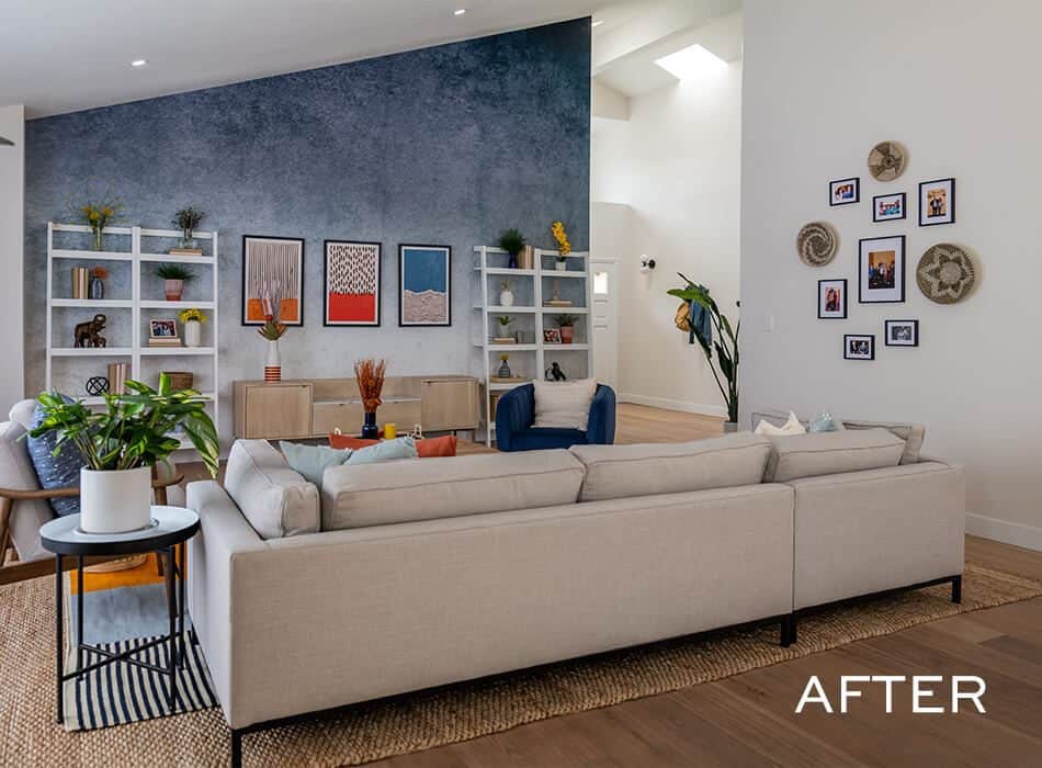 Modern living room with a neutral sectional sofa, a blue accent wall, open shelving, and decorative wall art
