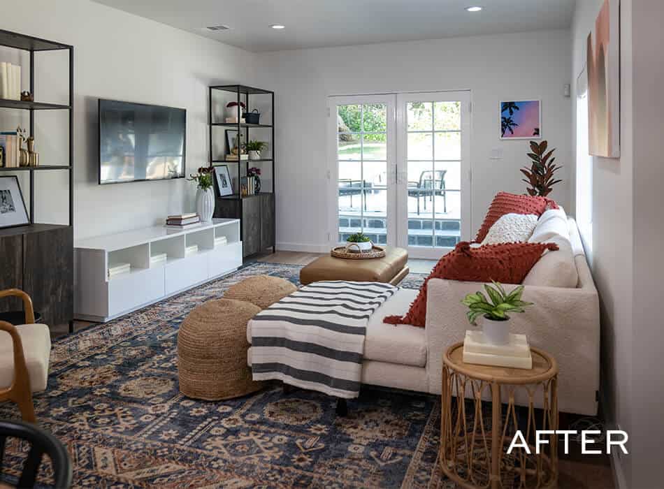Cozy living room with white sectional sofa, patterned rug, ottoman, and wall-mounted TV