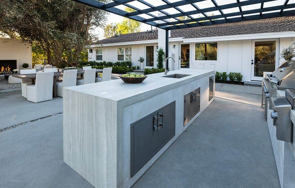 Outdoor kitchen with stone island, sink, stainless steel cabinets, and pergola