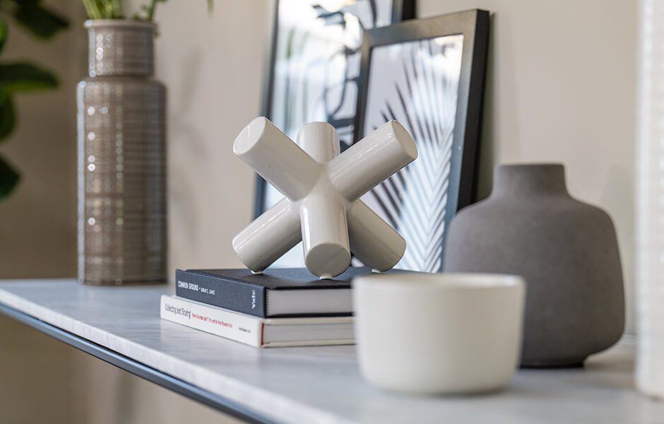 Decorative shelf with modern sculptures, books, and framed artwork
