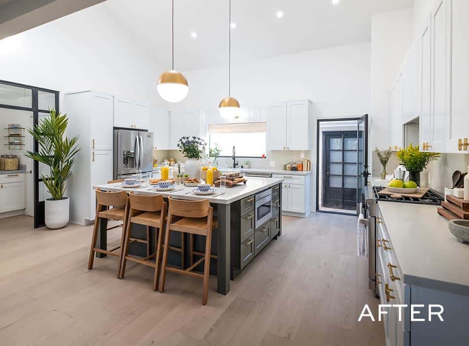 Bright modern kitchen with white cabinets, large island, wooden stools, and gold pendant lights