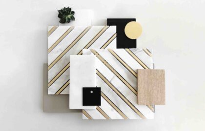 Flat lay of white marble with gold stripes, black marble, wood, gold foil, and a plant