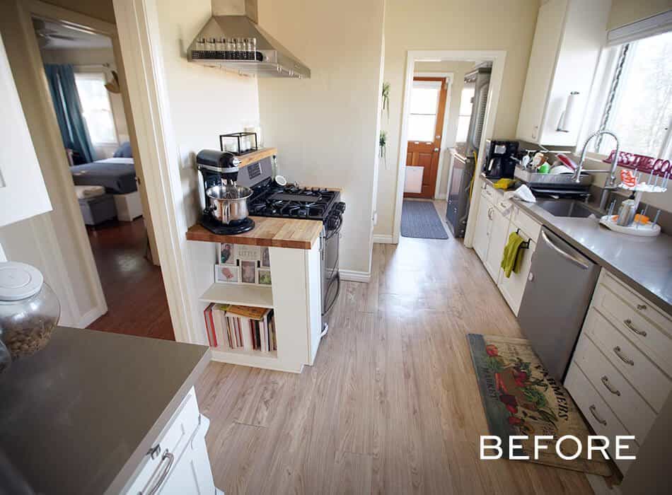Narrow kitchen with white cabinets, stainless steel appliances, and wooden flooring