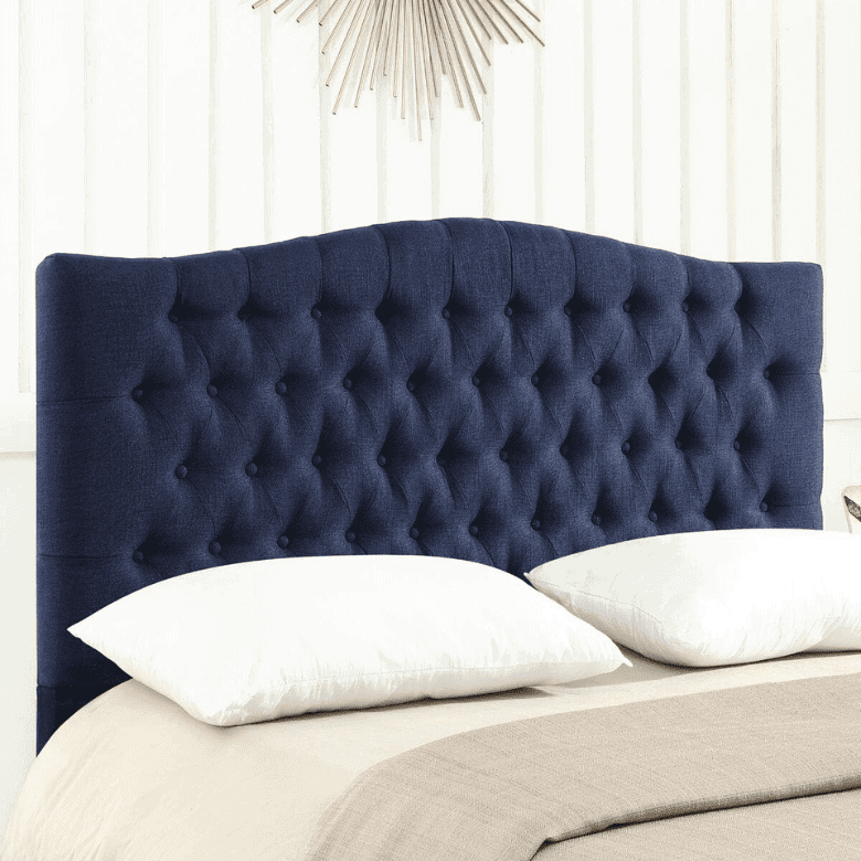 Navy blue tufted headboard with white pillows and neutral bedding