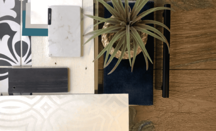 Material mood board featuring tile samples, wood swatches, and a potted plant on a textured surface