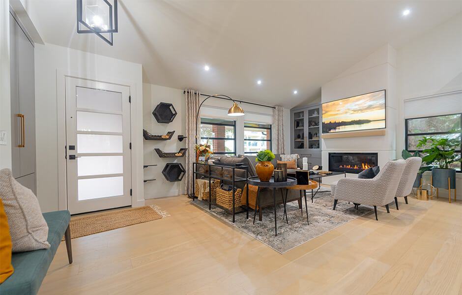 Spacious renovated living room with a fireplace, TV, sofa, armchairs, and plants