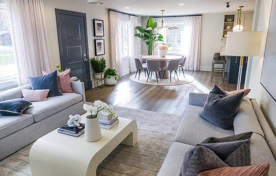 Modern living room with gray sofas, a white coffee table, and a dining area with large windows