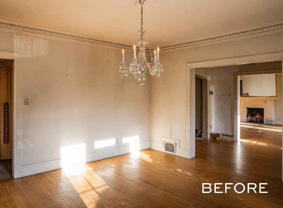 Empty dining room with worn walls, hardwood floors, a crystal chandelier